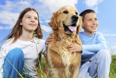 Young boy and girl sitting in grass with dog